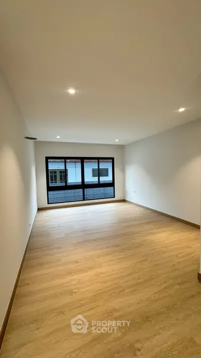 Spacious empty living room with wooden flooring and large window