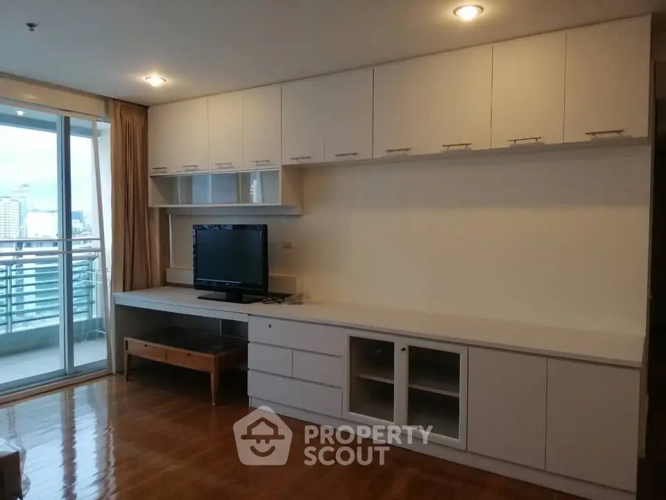 Spacious living room with built-in cabinets and city view balcony