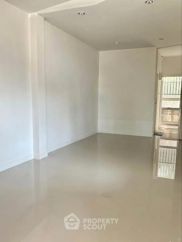 Spacious empty room with glossy tiled flooring and white walls, perfect for customization.