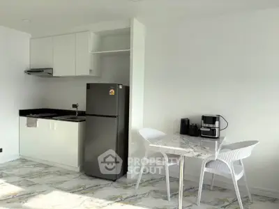 Modern kitchen with sleek appliances and dining area in bright, minimalist design.