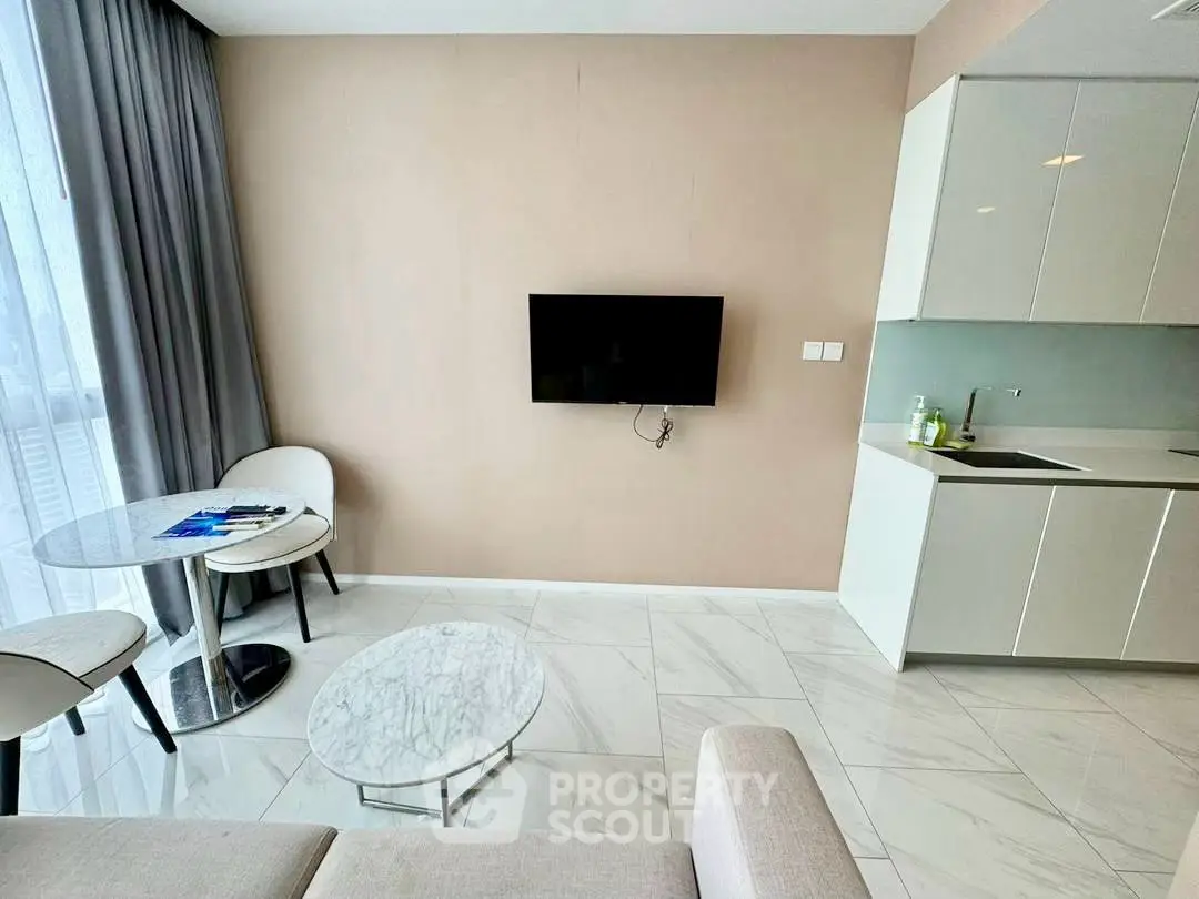 Modern living room with sleek kitchen and marble flooring, featuring a wall-mounted TV and elegant furniture.