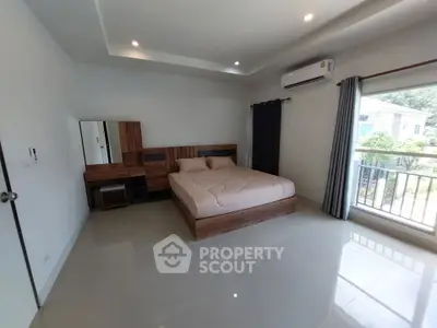 Spacious bedroom with modern furnishings and large window offering natural light and garden view.