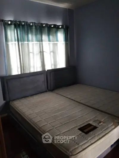 Cozy bedroom with twin mattresses and soft blue curtains.