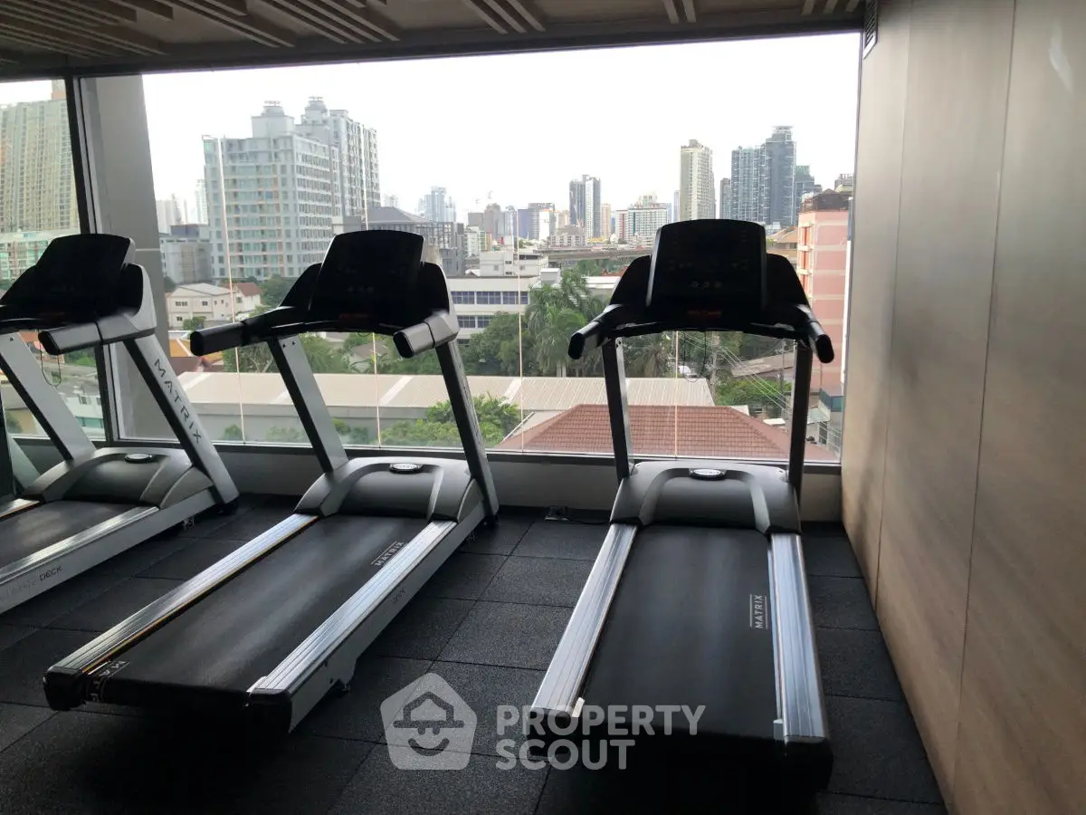 Modern gym with city view featuring treadmills and large windows.