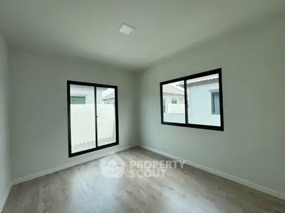 Bright and spacious empty room with large windows and wooden flooring, perfect for customization.