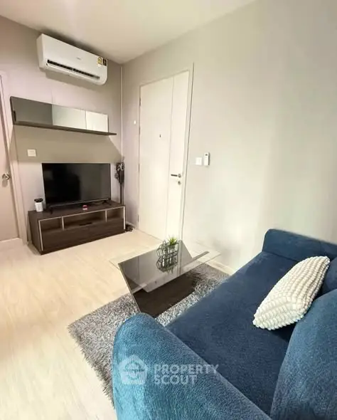 Modern living room with blue sofa, TV, and air conditioning in a cozy apartment.