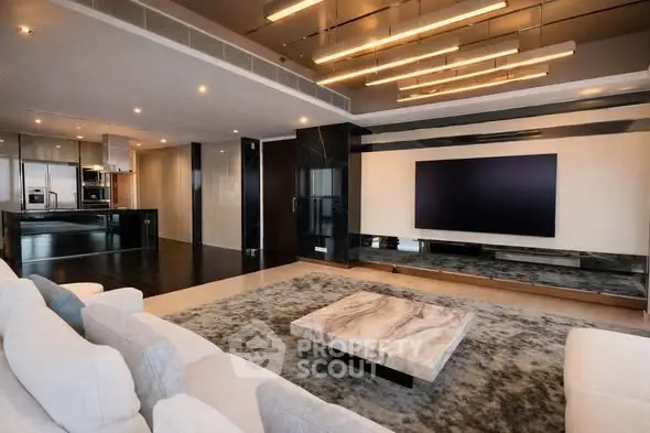 Luxurious modern living room with sleek design and open kitchen layout, featuring a large TV and elegant lighting.