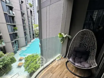 Luxurious balcony with hanging chair overlooking modern pool and lush greenery in upscale apartment complex.