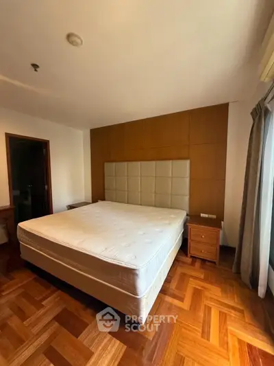 Spacious bedroom with wooden flooring and large bed in modern apartment