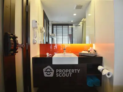 Modern bathroom with stylish sink and vibrant orange backsplash