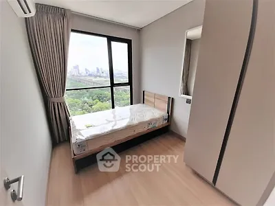Cozy bedroom with city view, featuring a single bed and large window for natural light.