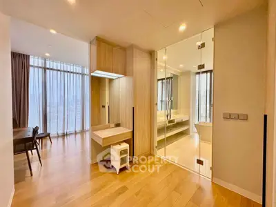 Spacious modern living area with wooden flooring and glass partition, featuring elegant dining space.