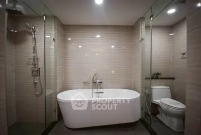 Luxurious modern bathroom with freestanding bathtub and glass shower enclosure.