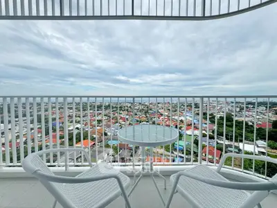 Stunning balcony view with modern furniture overlooking vibrant cityscape.