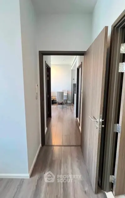 Spacious hallway leading to a modern living room with elegant wooden flooring.
