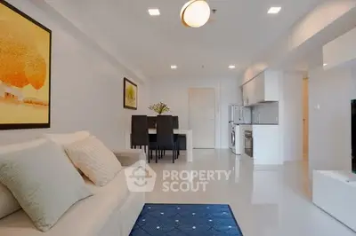 Modern living room with sleek furniture and open kitchen layout in a bright apartment.