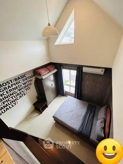 Cozy attic bedroom with unique triangular window, modern lighting, and sleek furnishings, perfect for a restful retreat in a stylish home.