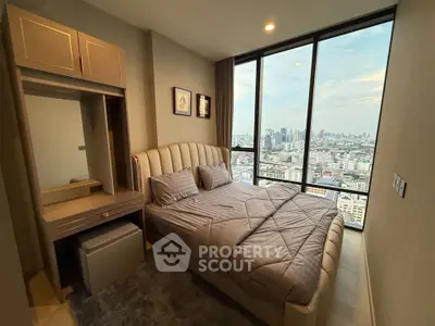 Luxurious bedroom with stunning city view from floor-to-ceiling windows in a high-rise apartment.