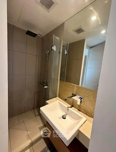 Modern bathroom with sleek shower and stylish sink in contemporary apartment.