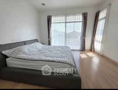 Spacious bedroom with large windows and modern bed, offering abundant natural light and serene ambiance.