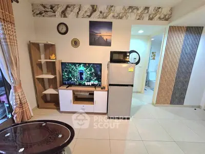 Modern living room with TV, fridge, and stylish decor in a cozy apartment.