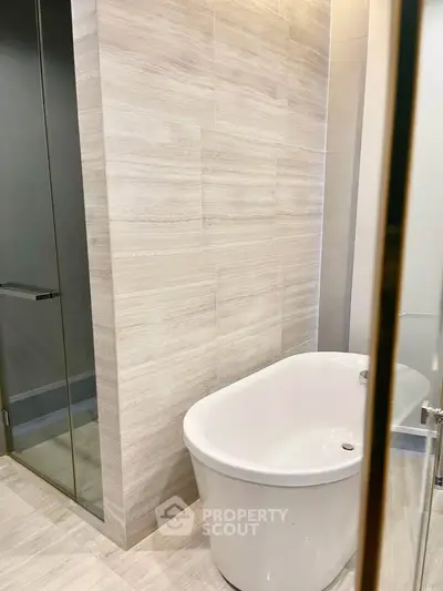 Modern bathroom with elegant freestanding bathtub and sleek glass shower enclosure.