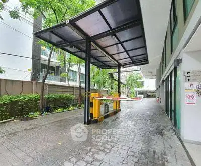 Modern building entrance with security gate and covered driveway