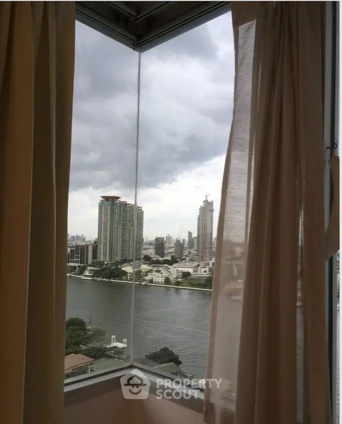 Stunning river view from high-rise apartment window with city skyline in the background.