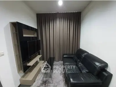 Cozy living room with modern black leather sofa and sleek TV setup.