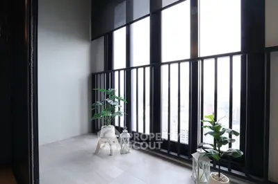 Bright indoor balcony with large windows and potted plants, offering a serene city view.