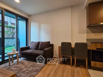 Modern living room with cozy sofa and dining area, featuring large windows and stylish decor.