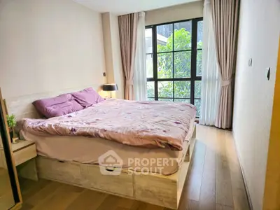 Cozy bedroom with large windows offering ample natural light, hardwood floors, and a serene ambiance perfect for relaxation.