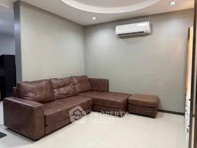 Modern living room with brown leather sectional sofa and air conditioning unit.