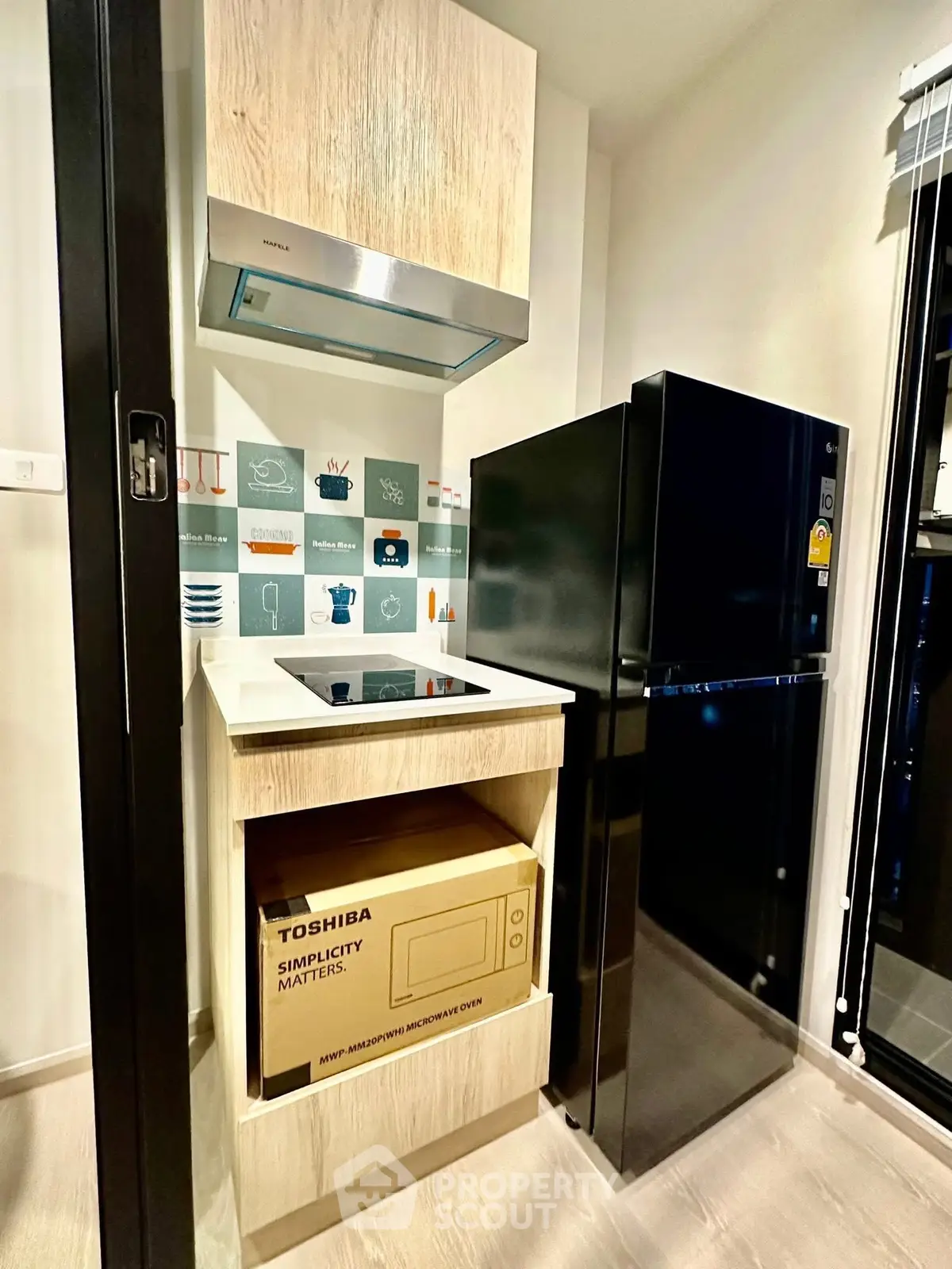 Modern compact kitchen with sleek appliances and stylish cabinetry in a contemporary apartment.