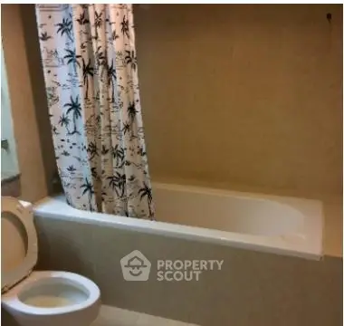 Cozy bathroom with bathtub and tropical-themed shower curtain in modern apartment.