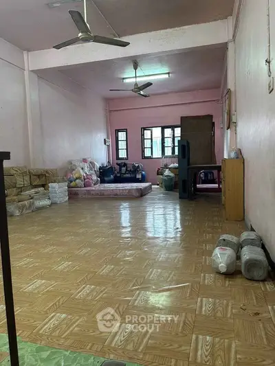 Spacious room with wooden flooring and ceiling fans, ideal for versatile living arrangements.