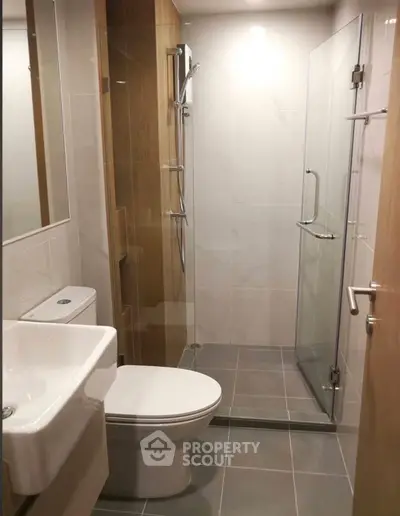 Modern bathroom with glass shower and sleek fixtures in contemporary apartment.