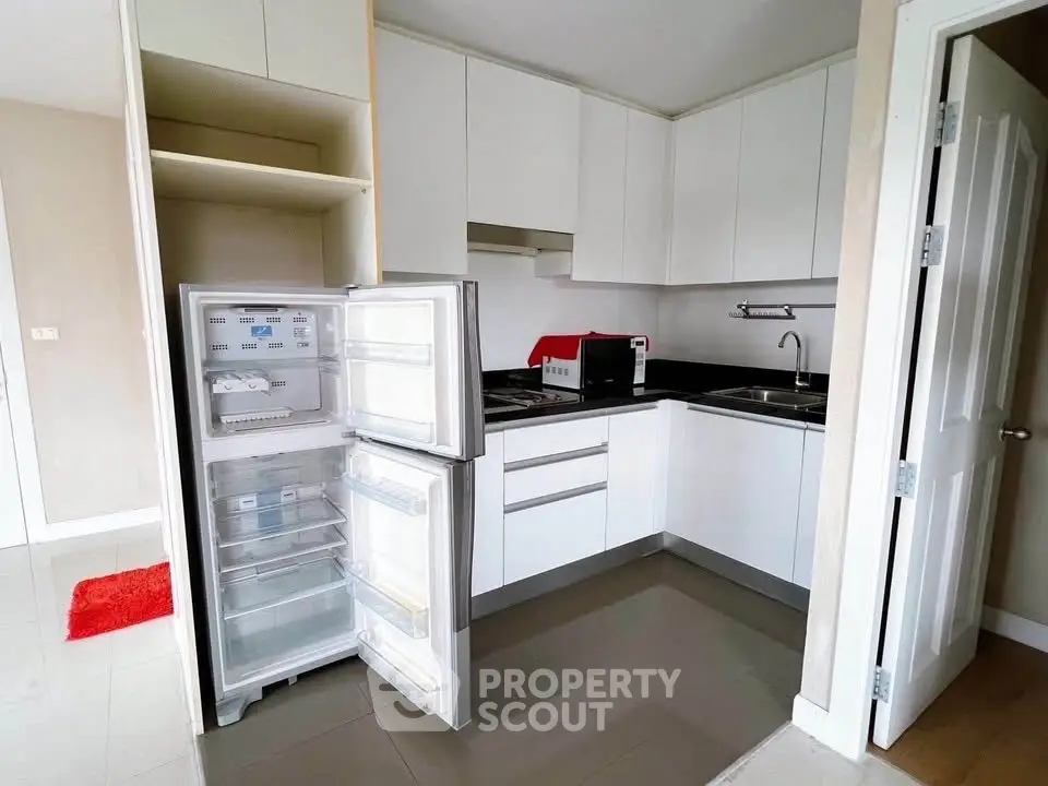 Modern kitchen with open fridge and sleek cabinetry in a stylish apartment.