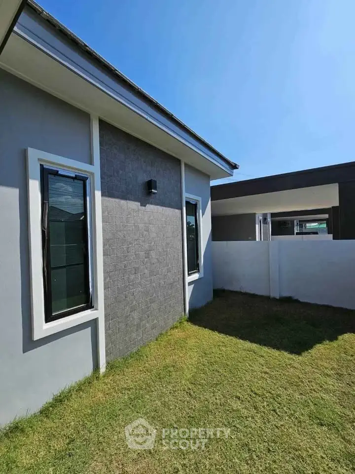 Modern exterior view of a stylish home with sleek design and lush green lawn.