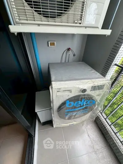 Compact balcony with washing machine and air conditioning unit in modern apartment.