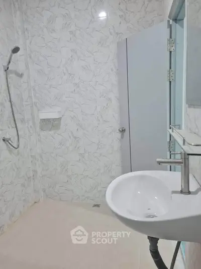 Modern minimalist bathroom with sleek fixtures and marble tile walls.