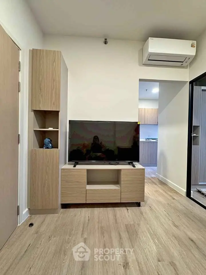 Modern living room with sleek wooden furniture and mounted TV, featuring a minimalist design and air conditioning.
