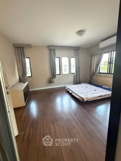 Spacious bedroom with hardwood floors and large windows for natural light.