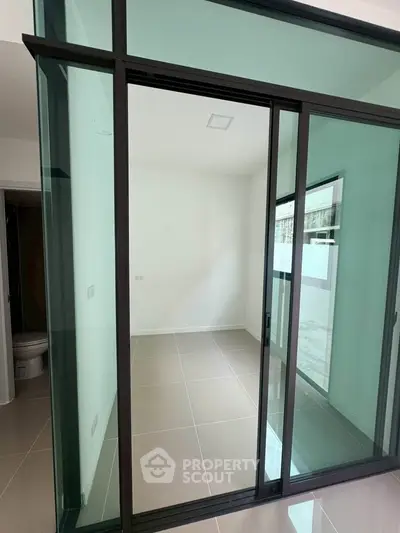 Modern interior space with glass sliding doors and tiled flooring, ideal for versatile use.