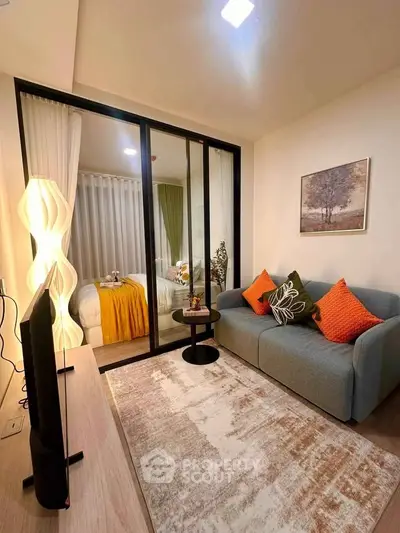 Modern living room with cozy sofa and stylish decor, featuring a view into a chic bedroom through glass doors.