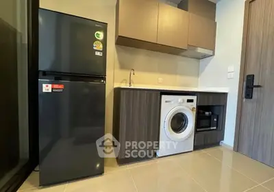 Modern kitchen with fridge, washing machine, and microwave in sleek cabinetry.