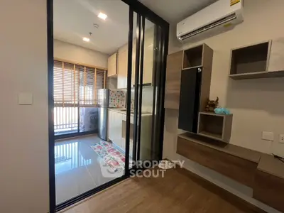 Modern condo interior with glass sliding doors and compact kitchen