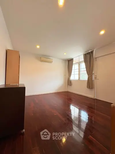 Spacious living room with polished wooden floors and large window for natural light.