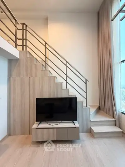 Modern duplex living room with stylish staircase and large window view.