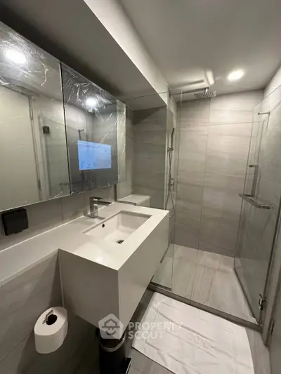 Modern bathroom with sleek design, glass shower, and large mirror.